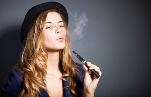 Elegant woman smoking e-cigarette with smoke wearing suit