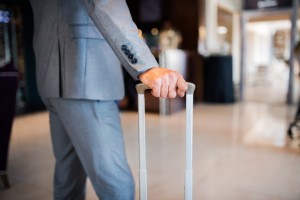 Unrecognizable businessman with suitcase in a hotel entrance hall.